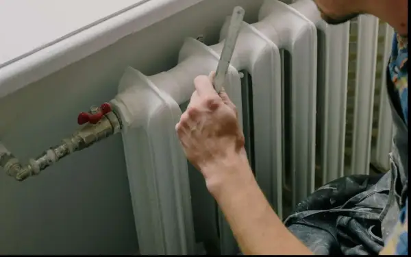Mano che misura il detentore del termosifone con un righello.