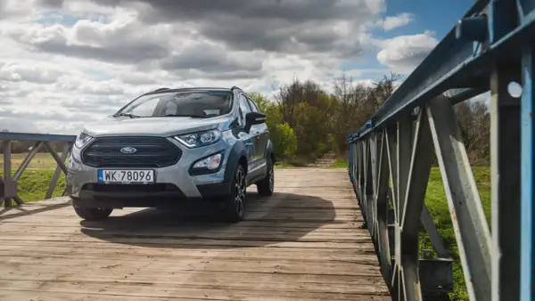 Srebrny Ford Ecosport na drewnianym moście, gotowy na przygodę.