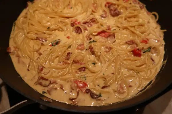 En krämig pasta med knaprigt bacon och tomater i en panna. Enkel och god vardagsmat.