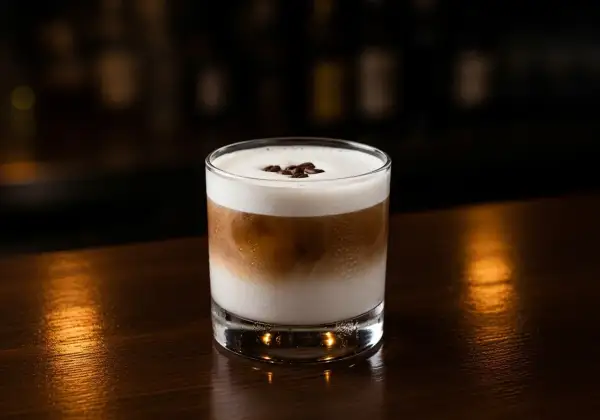 En krämig White Russian med kaffebönor på toppen, perfekt för en mysig kväll.