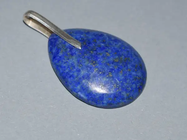 Owalny wisiorek z lapis lazuli, kamienia o intensywnie niebieskim kolorze i złotych inkluzjach. Jego właściwości od wieków cenione są w ezoteryce.