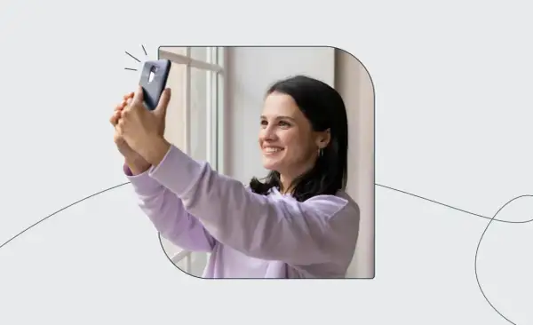 Uśmiechnięta dziewczyna robi selfie telefonem, zastanawiając się, ile zdjęć do dowodu będzie potrzebować.