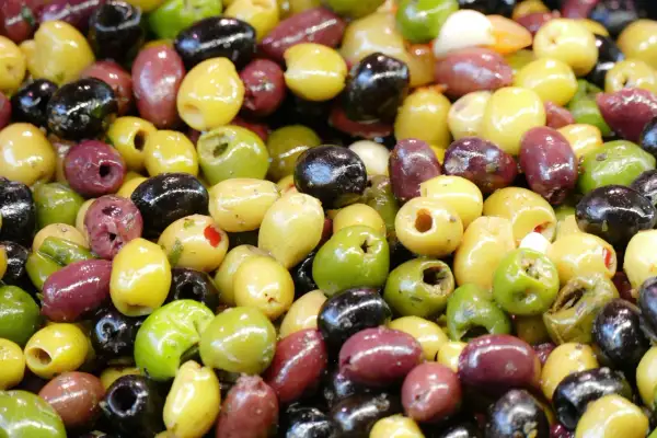 Un assortimento colorato di olive dolci varietà: verdi, nere e viola, alcune denocciolate, pronte per essere gustate.