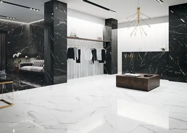 Elegancki butik z czarnymi ścianami w żyłach nero marquina i białymi podłogami. Wieszaki z ubraniami, kanapa i lada recepcyjna.