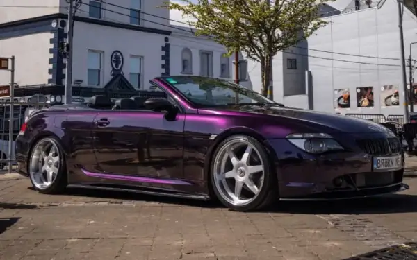 Fioletowe BMW E64 kabriolet z chromowanymi felgami stoi na ulicy.