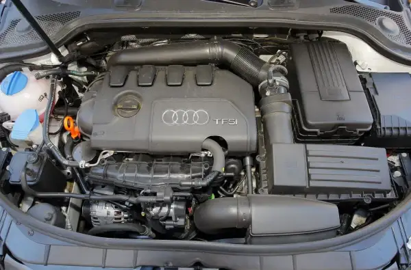 Silnik TFSI w Audi 8P. Widoczne elementy układu dolotowego, zbiornik płynu chłodniczego i alternator.