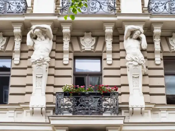 Dwie rzeźby atlantesów podtrzymują balkon z kwiatami. To przykład stylu secesja, co to za sztuka!