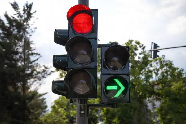 Sygnalizacja świetlna z czerwonym światłem na górze i zieloną strzałką po prawej. Czas jechać!