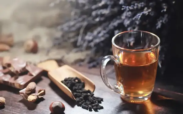 Un thé ambré dans une tasse, du chocolat, des noisettes et des feuilles de thé. Idéal pour le temps conservation thé infusé.