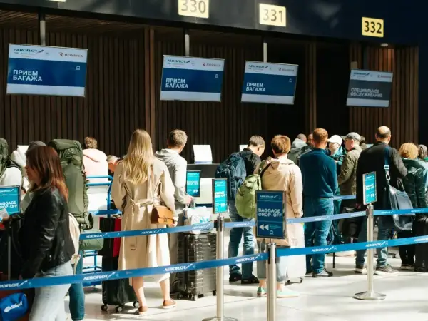 Kolejka do odprawy bagażowej. Na ekranach widnieje napis "BAGGAGE DROP-OFF", ale nie ma żadnego "no show".