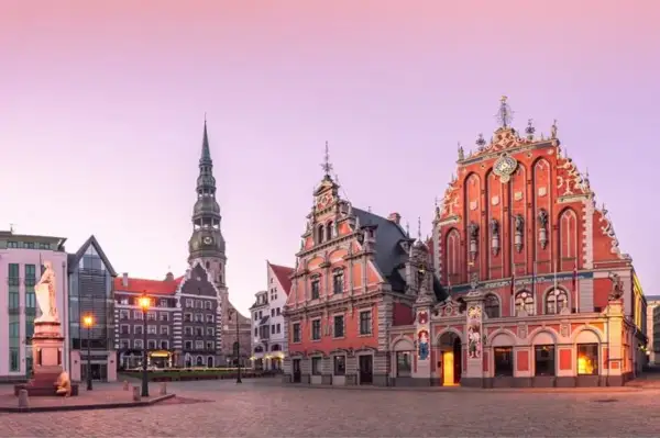 Ratusz i Dom Bractwa Czarnogłowych w Rydze, z wieżą kościoła św. Piotra w tle, o wschodzie słońca.