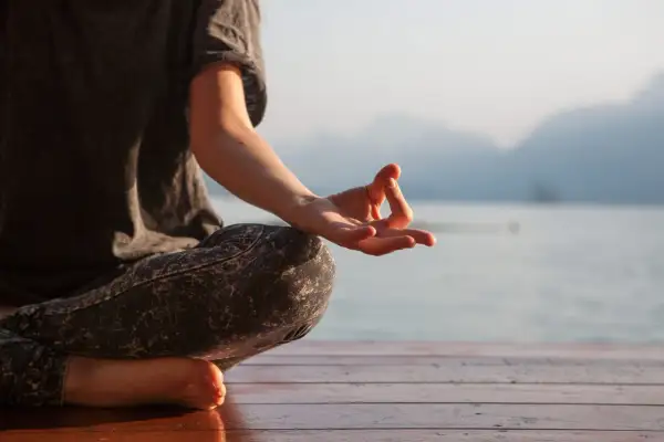 Persona meditando en posición de loto, con la mano en mudra Gyan, susurrando el mantra om.