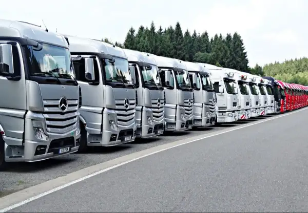 Rangée de camions Mercedes-Benz argentés et blancs, prêts pour le transport. La réglementation stationnement poids lourds est respectée.