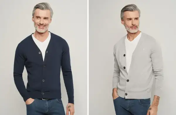 Elegancki mężczyzna pokazuje, jak nosić kardigan – w granatowym i szarym kolorze, z białym t-shirtem i jeansami.