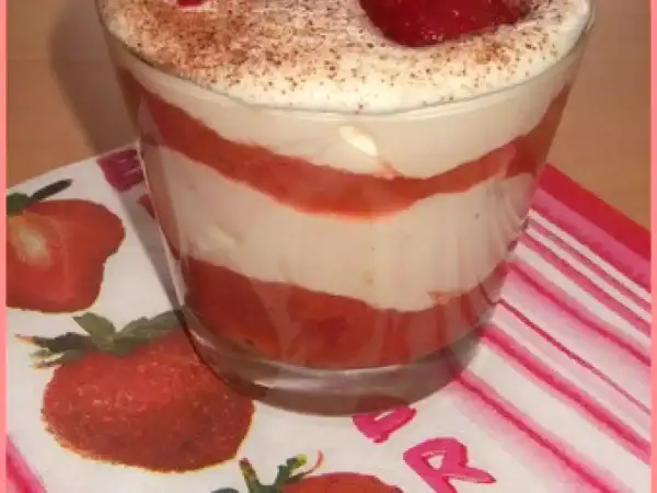 Un délicieux tiramisu rhubarbe fraise, superposé en couches dans un verre, garni de fraises et de cacao.