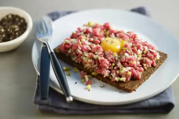 En läcker råbiff på mörkt bröd med en gul äggula i mitten. Perfekt för dig som söker ett gott råbiff recept.