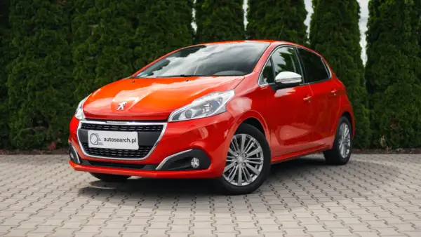 Czerwony Peugeot 208 z błyszczącymi światłami, idealny na egzamin na prawo jazdy.