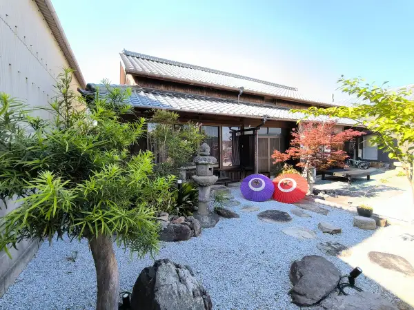 Tradycyjny dom na wyspie Japonii z Kagawa, z kamiennym ogrodem, parasolami i jesiennym drzewem klonowym.