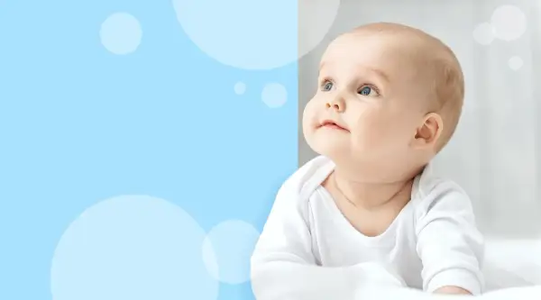 Urocze dziecko w białym body, z zaciekawieniem spogląda w górę. Czyżby miało wysypkę kaszkę?