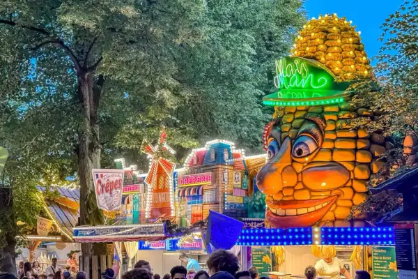 Buntes Volksfest mit Maiskolben-Figur und Buden. Das bergkirchweih erlangen programm lockt mit Leckereien.