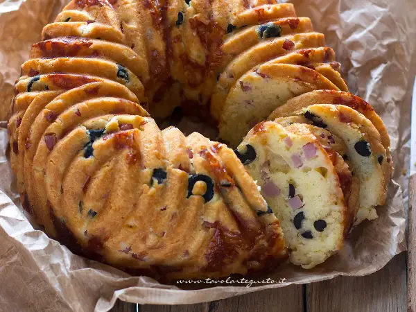 Una golosa ciambella salata napoletana, ricca di olive nere e cubetti di prosciutto, pronta per essere gustata.