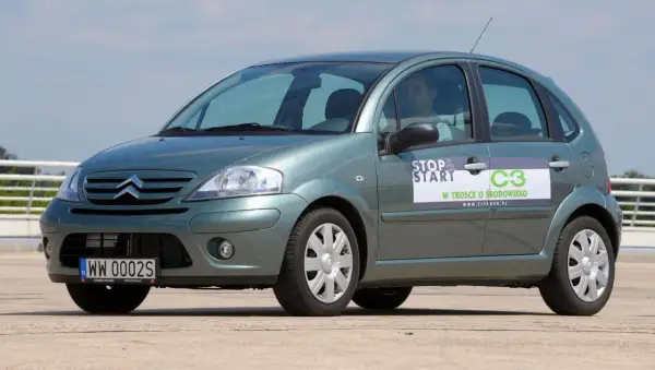 Zielony Citroen C3 z naklejką "Stop & Start" i informacją "W trosce o środowisko". Widać przednie żarówki.