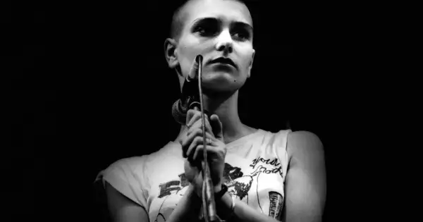 Sinéad O'Connor śpiewa "Nothing Compares 2 U", jej twarz jest oświetlona, a ona trzyma mikrofon.