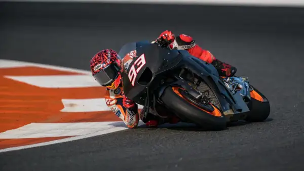 Piloto de MotoGP inclinado en curva, con su moto negra y naranja. La potencia de cuántos caballos tiene una MotoGP es asombrosa.