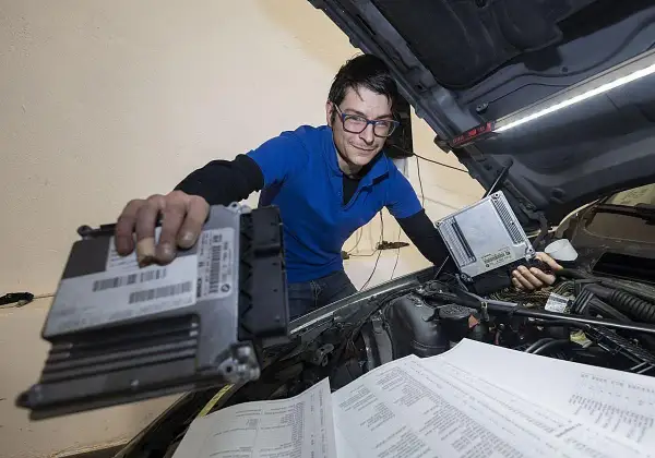 Técnico con gafas revisa unidades de control para modificaciones coche.
