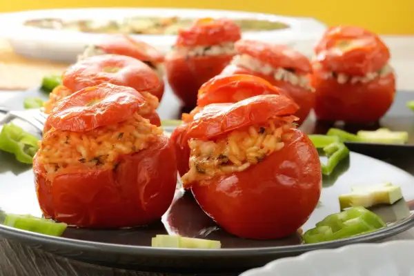 Pomodori ripieni di riso, un piatto gustoso e colorato, serviti su un piatto scuro con peperoni verdi.