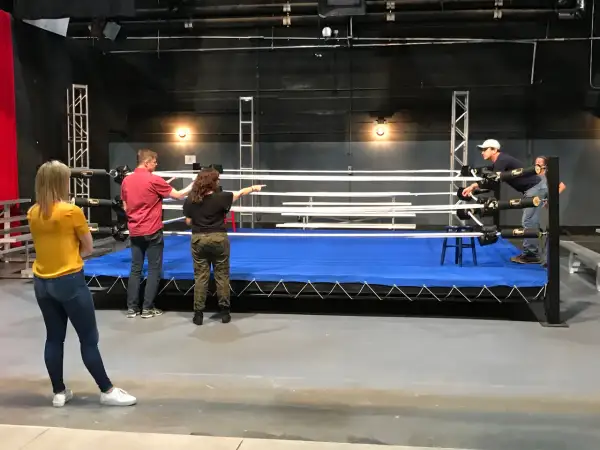 A group discusses a 12 week boxing training program around a wrestling ring.