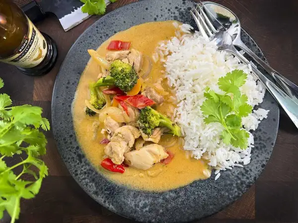 En smakrik thaigryta med kyckling, broccoli och paprika i en krämig sås, serverad med fluffigt ris.
