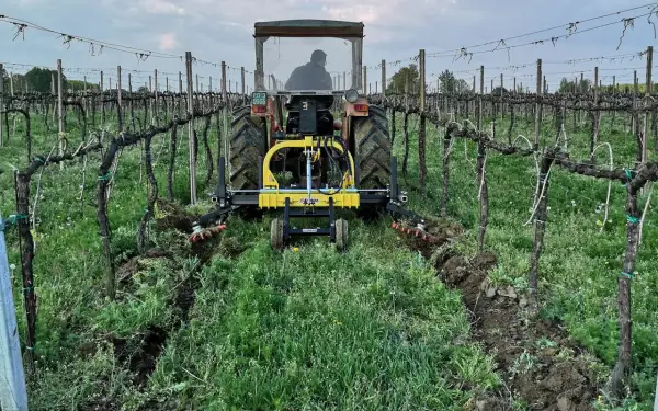 Trattore in vigneto con attrezzo per la lavorazione del terreno, un esempio di moderna resa agricola.