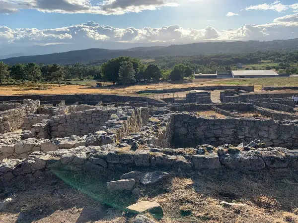 Ruinas de piedra en San Amaro, Ourense, bajo un cielo nublado y sol radiante.