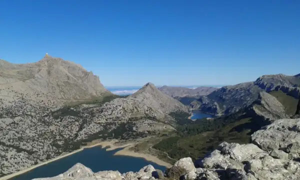 Vistas impresionantes desde el Puig de sa Rateta, con embalses y montañas escarpadas bajo un cielo azul.
