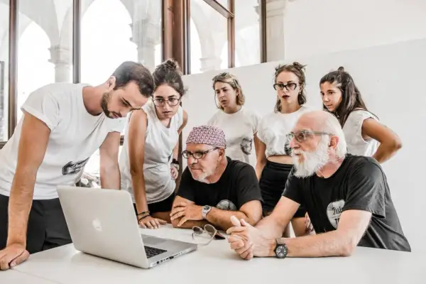 Stefano Guindani e un gruppo di giovani analizzano un progetto al computer, concentrati e seri.