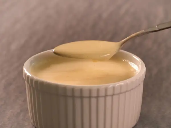 Cremige Vanillesauce, frisch zubereitet, auf einem Löffel. Perfekt zum vanillesauce selber machen.
