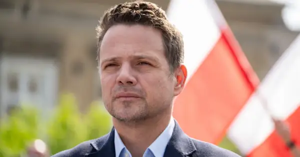 Rafał Trzaskowski, którego wiek jest często dyskutowany, na tle biało-czerwonych flag.