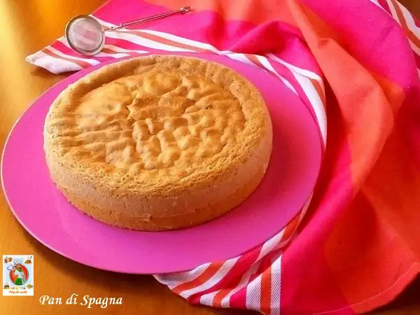 Gâteau Pan di Spagna, parfait pour une recette génoise moelleuse. Servi sur une assiette rose avec un torchon coloré.