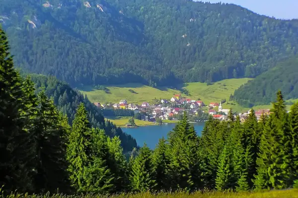 Idyllisches Dorf am See, umgeben von grünen Hügeln und Nadelwäldern. Perfekt für Slowakei Reisetipps!