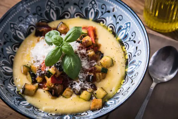 Cremige Polenta mit gebratenem Gemüse, Parmesan und Basilikum. Was ist Polenta? Ein herzhaftes Gericht aus Maisgrieß.