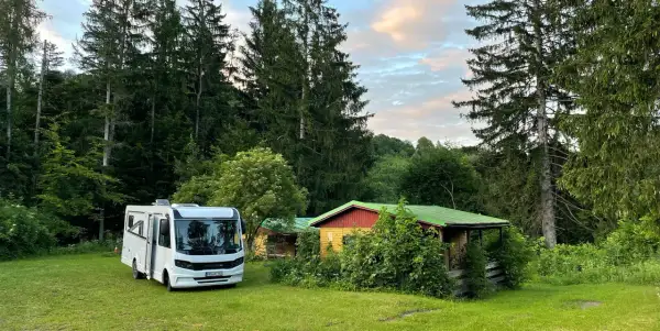 Wohnmobil neben bunten Hütten im Wald, ein idyllischer Ort nahe Banská Štiavnica.