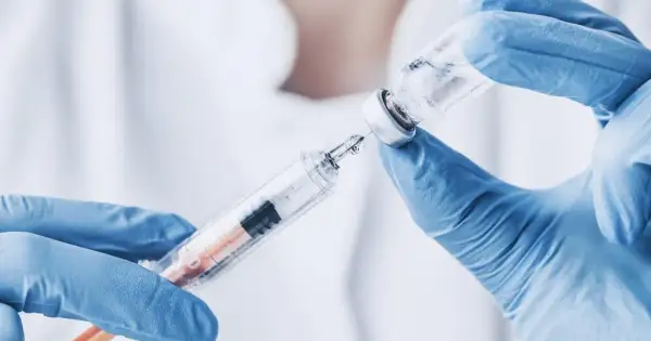 Ręce w niebieskich rękawiczkach pobierają płyn z fiolki do strzykawki. To może być propofol, środek znieczulający.