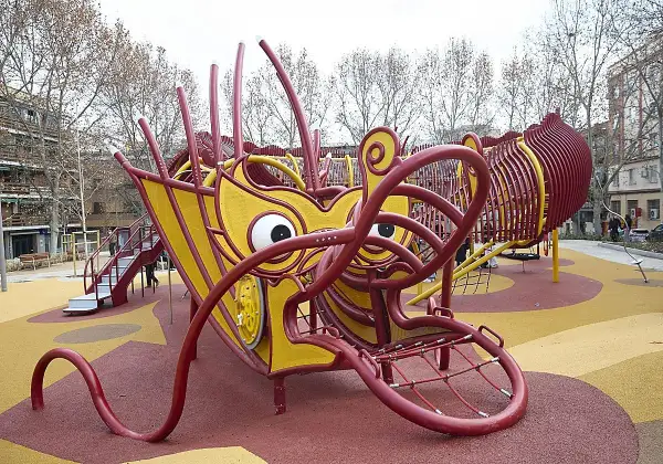 Un parque infantil con forma de dragón amarillo y rojo en Usera. ¡Un lugar genial que ver en Usera para los niños!