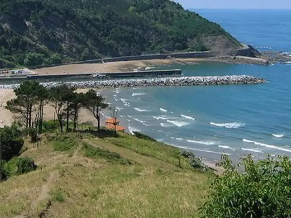 La playa mas cercana a Logroño, con olas rompiendo en la arena y un rompeolas protegiendo el puerto.