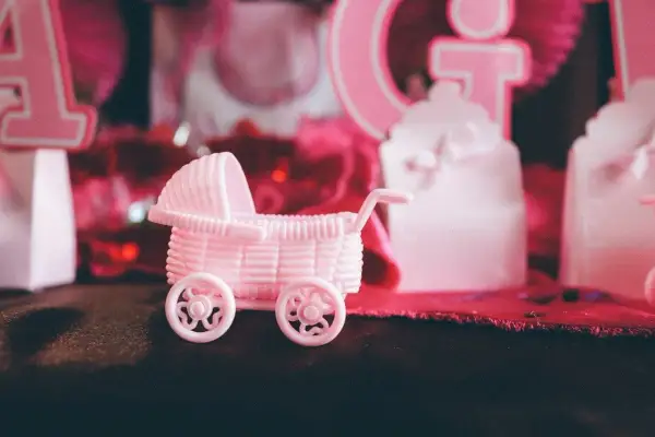 Różowy wózek dla lalek na przyjęciu gender reveal. Czy to będzie dziewczynka?
