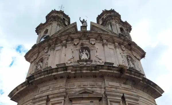 La imponente fachada de la iglesia de la Virgen Peregrina se alza bajo un cielo nublado, con sus torres y estatuas de piedra.