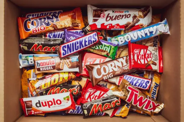 Pudełko pełne słodyczy: Snickers, Mars, Twix, Bounty, Kinder Bueno, Corny, Duplo i inne popularne polskie marki słodyczy.