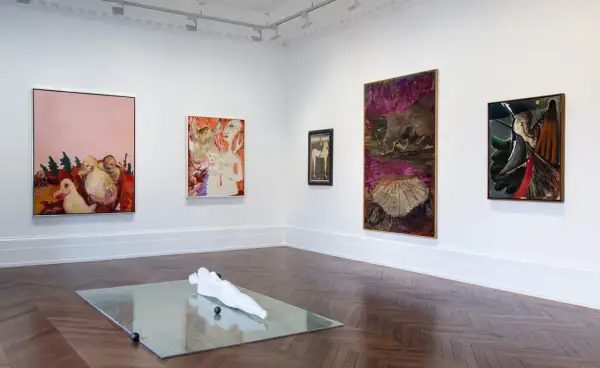 Artistic display at Michael Werner Gallery featuring abstract paintings and a sculpture on a mirrored surface.