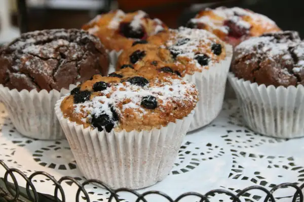 Muffins med blåbär och choklad, pudrade med florsocker. Bakpulver gör dem fluffiga och luftiga.